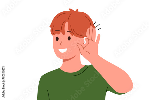 Boy uses hearing aid and puts palm to ear, rejoicing at availability of technological solutions to health problems. Schoolboy with hearing aid smiles listening to sounds around him.