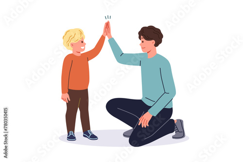 Father supports young son by high-fiving boy and raising child on own after divorce from mother. Young single dad smiles while communicating with son, celebrating father family day