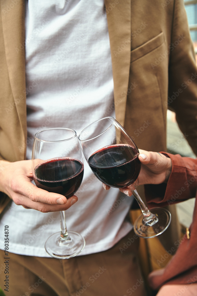 A stylish man with a glass in each hand filled with red wine, showcasing elegance and sophistication
