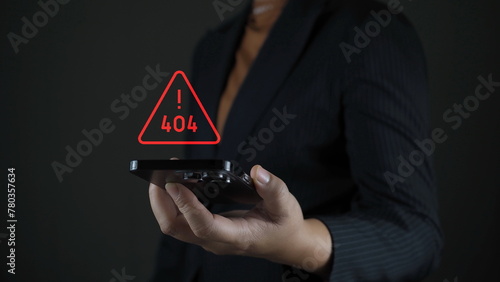 Businessman holding smartphone with red triangle caution warning sign for notification error and maintenance concept.