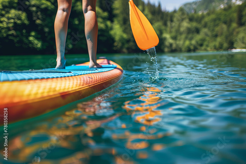 Fototapeta Naklejka Na Ścianę i Meble -  Active Summer: young woman on a vibrant colored paddleboard race on a calm lake