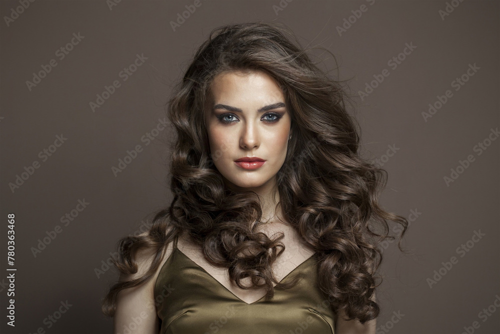 Lovely young brunette female model with long brown wavy hair and makeup closeup portrait