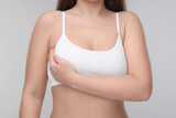 Mammology. Woman doing breast self-examination on light grey background, closeup