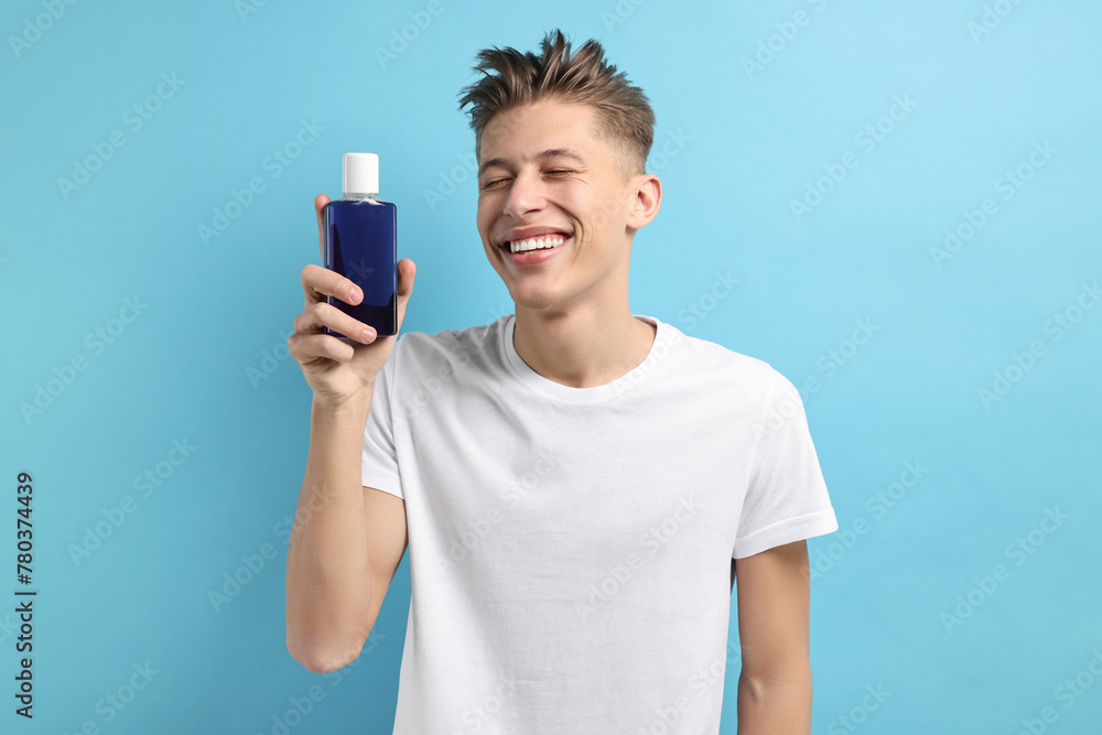 Young man with mouthwash on light blue background Young man with mouthwash on light blue background