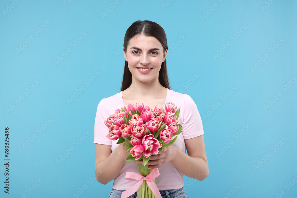 Happy young woman with beautiful bouquet on light blue background Happy young woman with beautiful bouquet on light blue background