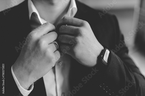 groom in a suit adjusts his shirt collar photo