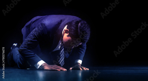 失敗し暗い部屋で跪き項垂れ絶望するスーツを着た仕事中のビジネスマンの日本人男性 後悔・謝罪・増税・落ち込む・鬱・破産のイメージ