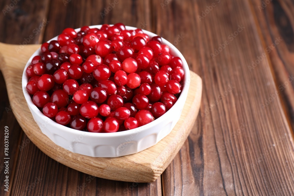Fresh ripe cranberries in bowl on wooden table, closeup Fresh ripe cranberries in bowl on wooden table, closeup
