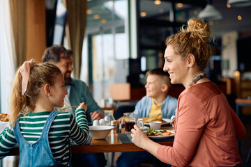 Happy girl and her mother enjoying in family breakfast in hotel.