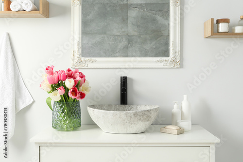 Fototapeta Naklejka Na Ścianę i Meble -  Vase with beautiful pink tulips and toiletries near sink in bathroom