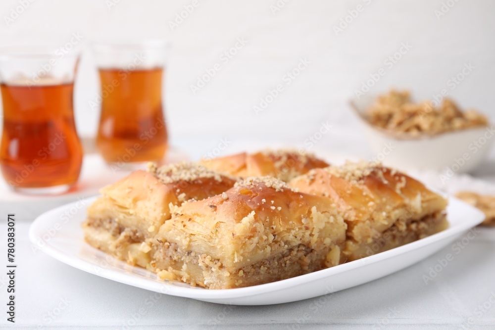 Eastern sweets. Pieces of tasty baklava and tea on white tiled table, closeup Eastern sweets. Pieces of tasty baklava and tea on white tiled table, closeup
