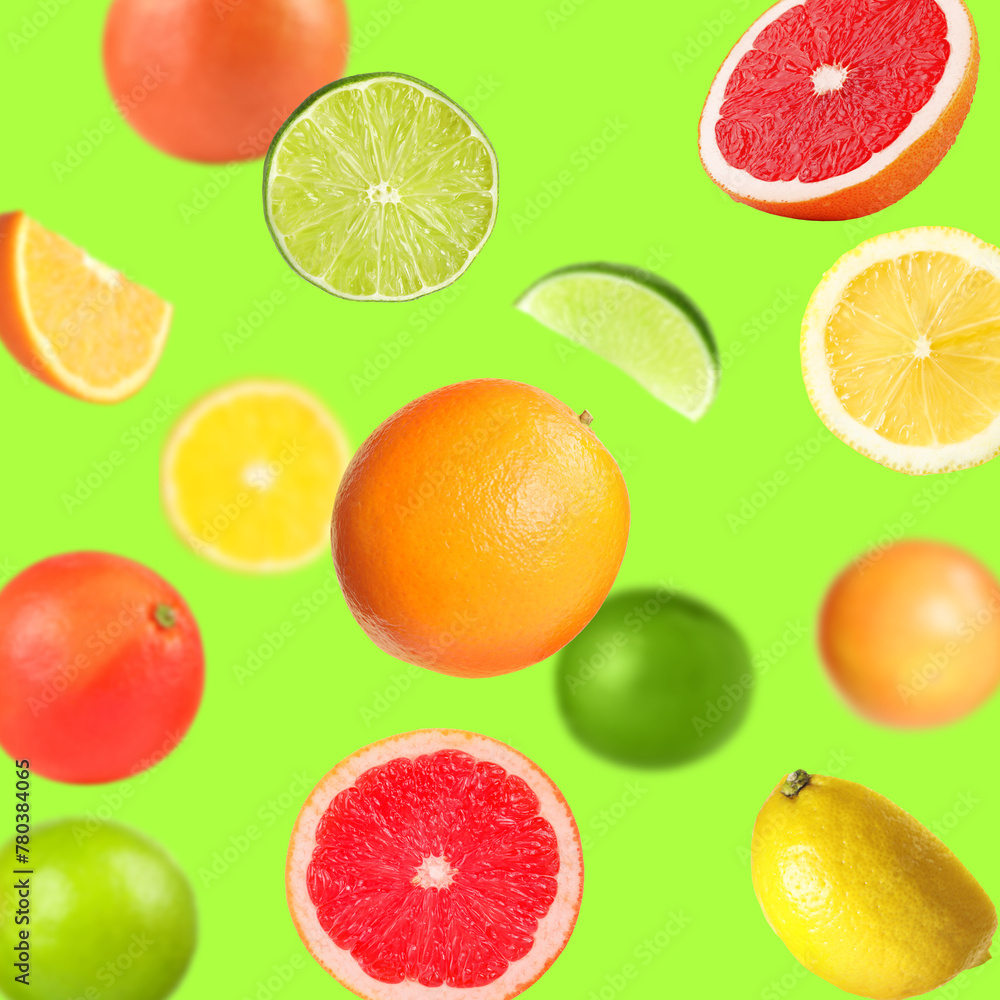 Many different fresh citrus fruits in air on light green background