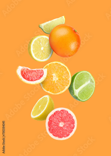 Fototapeta Naklejka Na Ścianę i Meble -  Many different fresh citrus fruits falling on orange background
