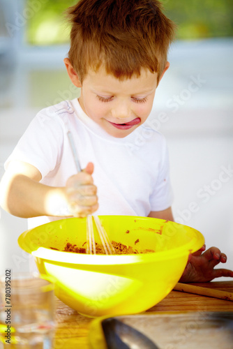 Boy, bowl or whip in baking, nutrition or playful activity as growth, development or milestone. Male child, naughty or mixing of food, ingredients or meal prep as sweet, dessert or snack in kitchen