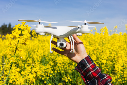 Technician holding an agriculture drone to control rapeseed crop. Innovation and smart agricultural technology for control and monitoring of crop pests and diseases