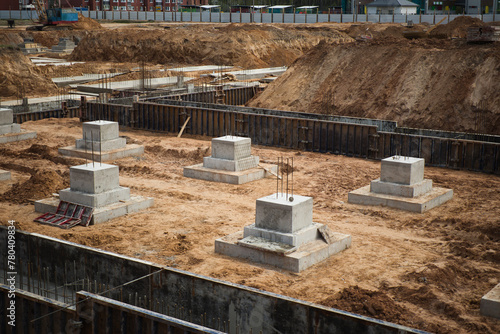 A construction site with reinforced concrete blocks in the foreground, showcasing the buildings beginning stages