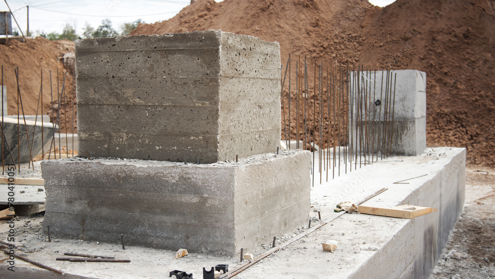 A collection of concrete blocks rests peacefully on a dusty construction site, waiting to be utilized for building reinforced foundations A collection of concrete blocks rests peacefully on a dusty construction site, waiting to be utilized for building reinforced foundations