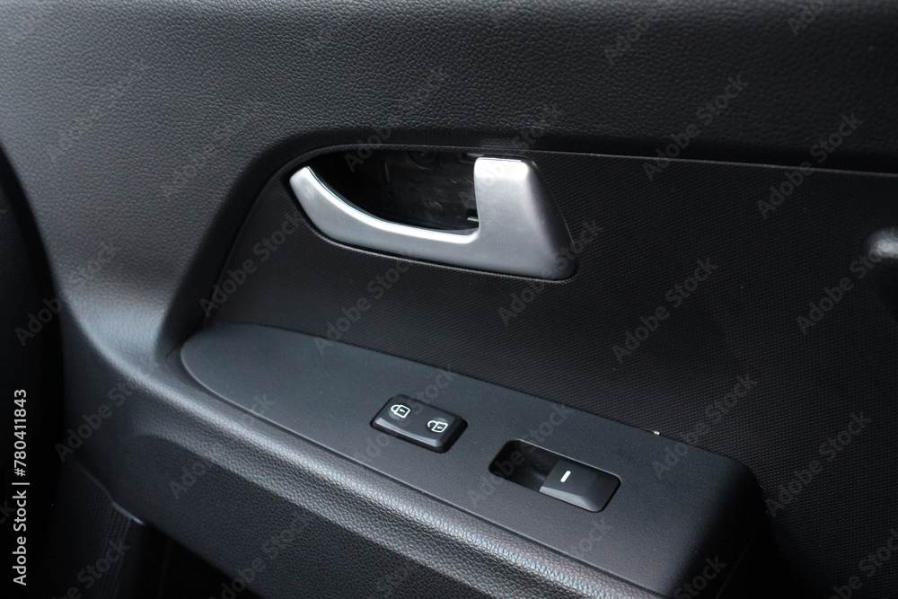 Passenger door trim. Car window controls. Door handle with power window control. Window control buttons on cars. Car interior details of door handle with windows controls and adjustments. 