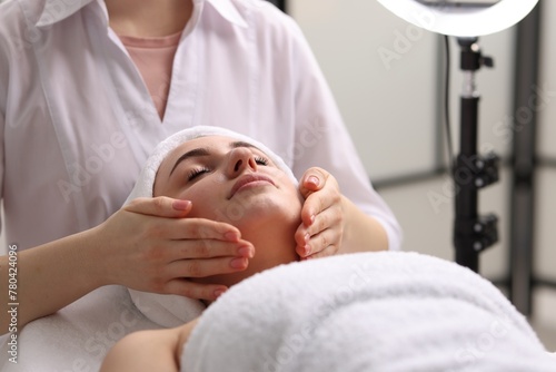 Cosmetologist making face massage to client in clinic, closeup