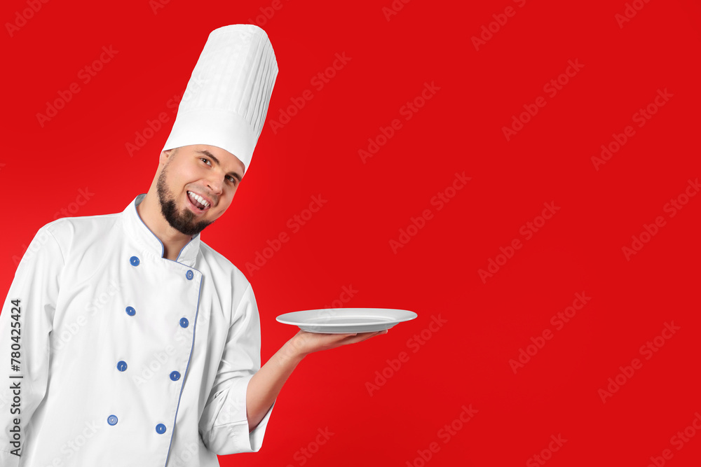 Happy professional confectioner in uniform holding empty plate on red background. Space for text Happy professional confectioner in uniform holding empty plate on red background. Space for text