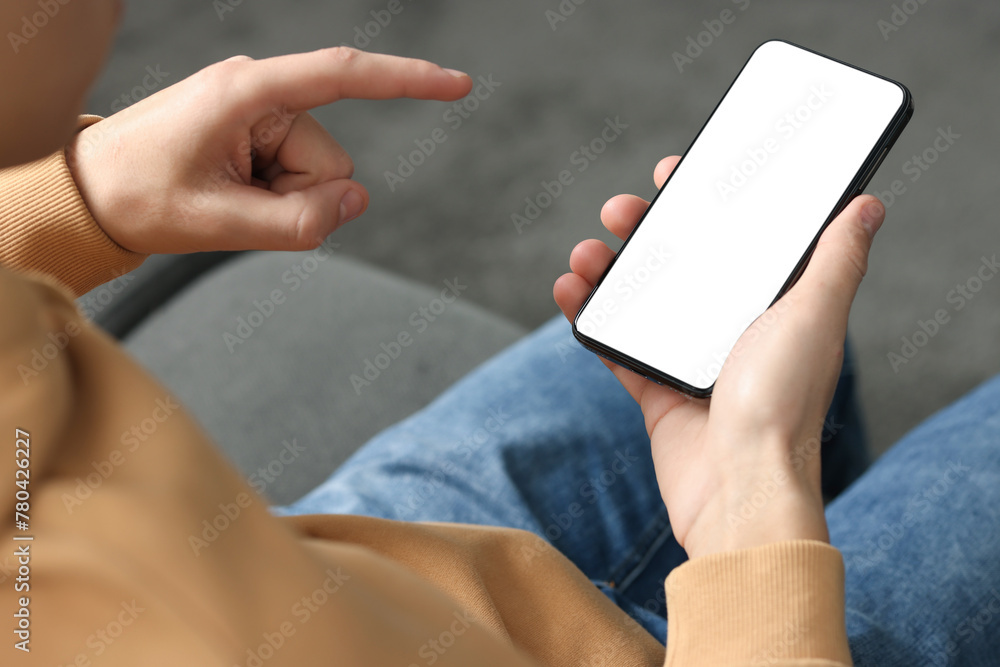 Man using smartphone with blank screen indoors, closeup. Mockup for design Man using smartphone with blank screen indoors, closeup. Mockup for design