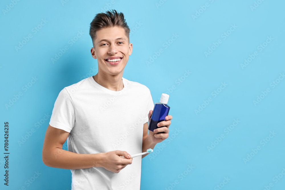Young man with mouthwash and toothbrush on light blue background, space for text Young man with mouthwash and toothbrush on light blue background, space for text