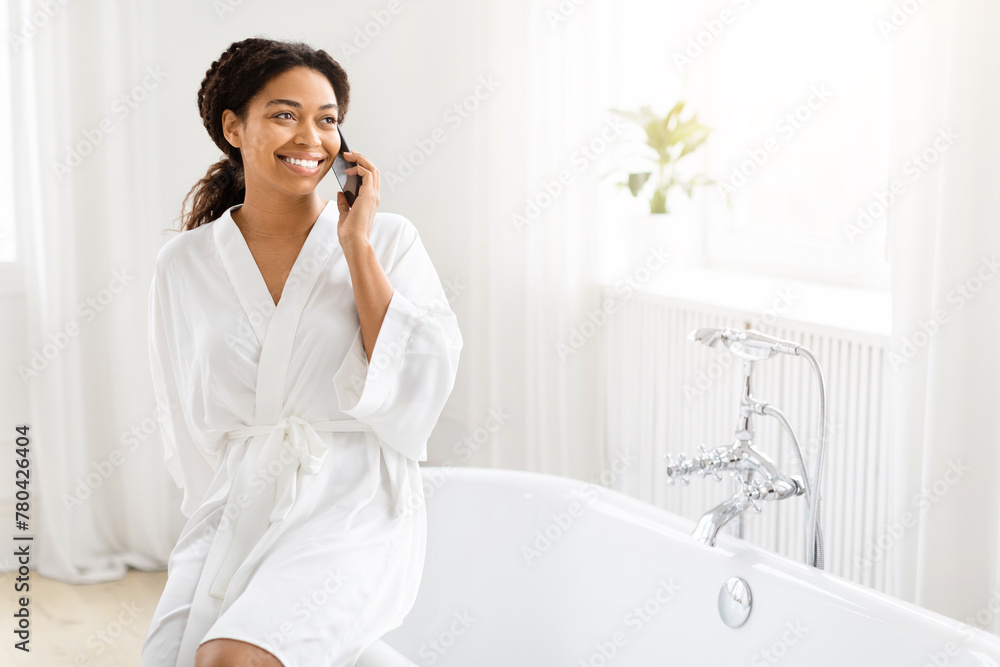Happy woman talking on phone while sitting on tub Happy woman talking on phone while sitting on tub