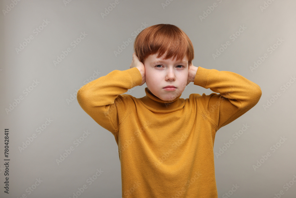 Hearing problem. Little boy suffering from ear pain on grey background, space for text Hearing problem. Little boy suffering from ear pain on grey background, space for text