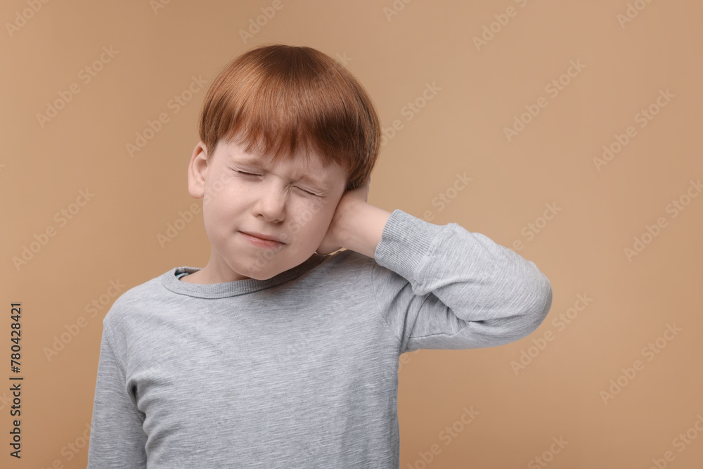 Hearing problem. Little boy suffering from ear pain on pale brown background, space for text Hearing problem. Little boy suffering from ear pain on pale brown background, space for text