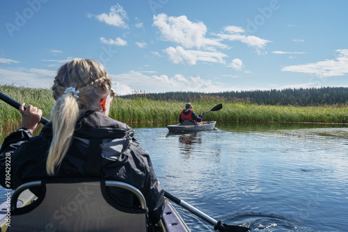 Senior man and woman kayaking in river on sunny day