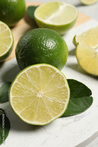 Fresh ripe limes and leaves on table, closeup