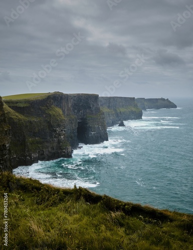 Scenic vertical view of the evergreen Cliffs of Moher in Ireland on a gloomy day