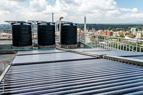 Water tank on the roof over blue sky. Black water tank on the roof of a tall building against a blue sky. water heating system on the roof of a high-rise building in southern countries. photo
