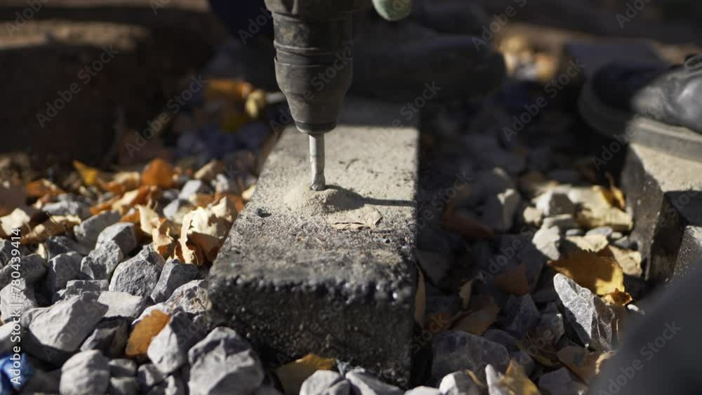 Seasoned builder drills hole in concrete beam with perforating machine closeup. Assembly of concrete structures at construction site Seasoned builder drills hole in concrete beam with perforating machine closeup. Assembly of concrete structures at construction site