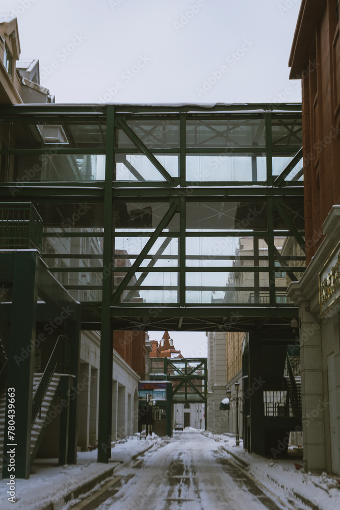 Glass corridor between the buildings above a snow-covered road Glass corridor between the buildings above a snow-covered road