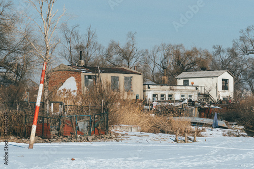 Rural houses on ice land with trees under a blue sky