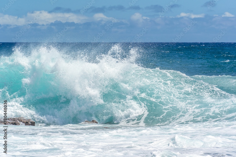 Beautiful shot of foamy blue sea waves crashing near the shore