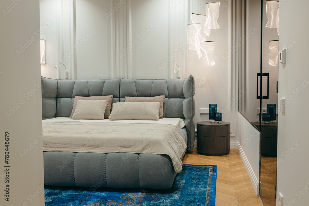 Fototapeta premium Bedroom with a bed, bedside table and lamps, with entrance to the bathroom