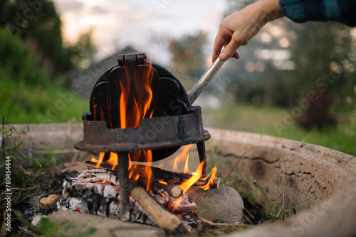 Cropped hand of man with waffle iron on camping stove in back yard photo