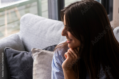 Relax and unwind. Young beautiful brunette woman with blissful facial expression alone on the sofa spending good time drinking coffee or tea in cup. Portrait of relaxed woman resting at home. Leisure