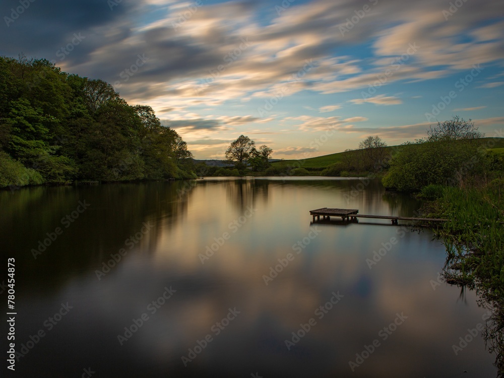 Fototapeta premium Landscape view with a lake reflectin sky and trees at sunset