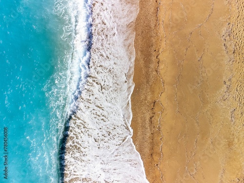 Aerial view of ocean waves crashing on a sandy beach