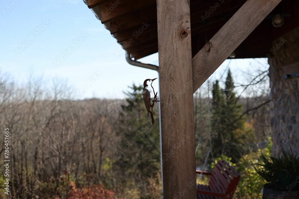 Metal bird on a wooden pole of the house.