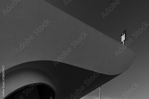 Black and white view of a console lamp behind a building during daytime