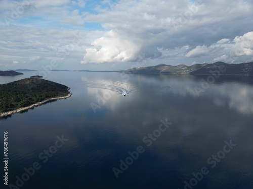 Aerial view of a ship driving on the sea with a small forested island photo