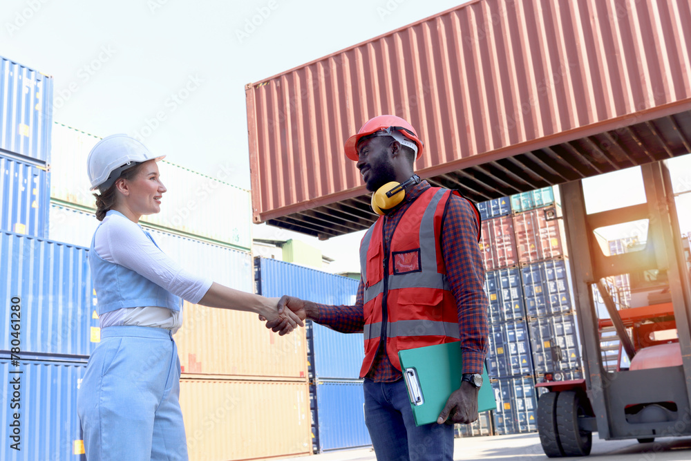 Two worker wearing safety helmet shaking hands at logistic shipping cargo containers yard. African American engineer man having hand shack with his beautiful young woman boss after work discussion. Two worker wearing safety helmet shaking hands at logistic shipping cargo containers yard. African American engineer man having hand shack with his beautiful young woman boss after work discussion.
