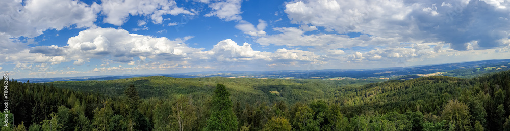 Panoramic view of a green landscape under a cloudy blue sky on a sunny day
