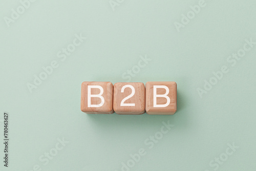 Wooden blocks with letters spelling B2B, representing Business-to-business, isolated on light green background