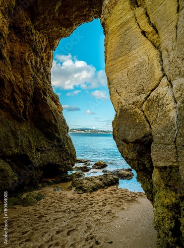 Vertical shot of the beach and sky spotted from inside the cave