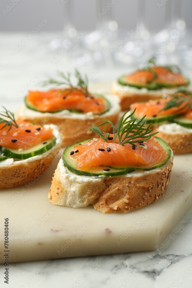 Tasty canapes with salmon, cucumber and cream cheese on white marble table, closeup Tasty canapes with salmon, cucumber and cream cheese on white marble table, closeup